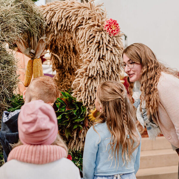 Erntedankfest / © Diözese Linz / Frauenkommission / Laurenz Kaiser Tamara Rennleithner, Leiterin des Pfarrcaritas-Kindergartens und der Pfarrcaritas-Krabbelstube in Pichl bei Wels, zeigt den Kindern die Erntekrone in der Kirche.