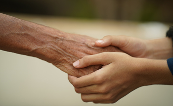 Junge Hände halten die Hand eines älteren Menschens